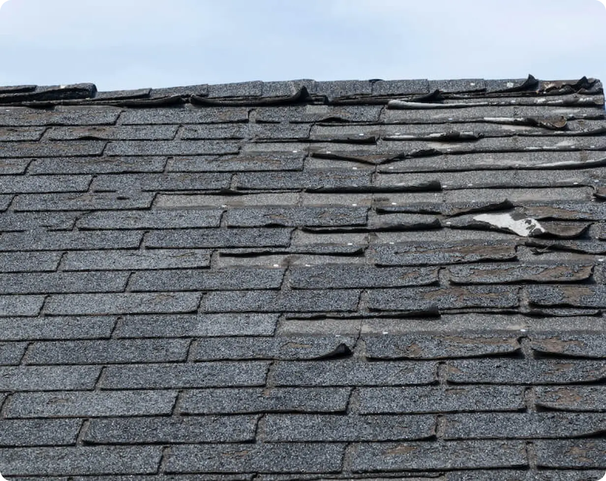 an image of an old roof with missing and curling shingles